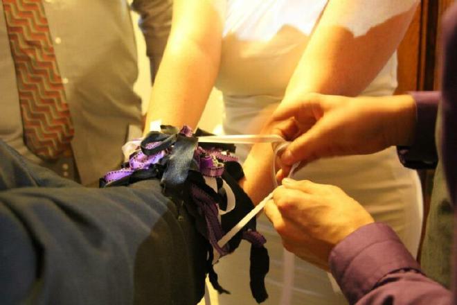 man and woman being tied together by ribbons in a polyamorous wedding ceremony